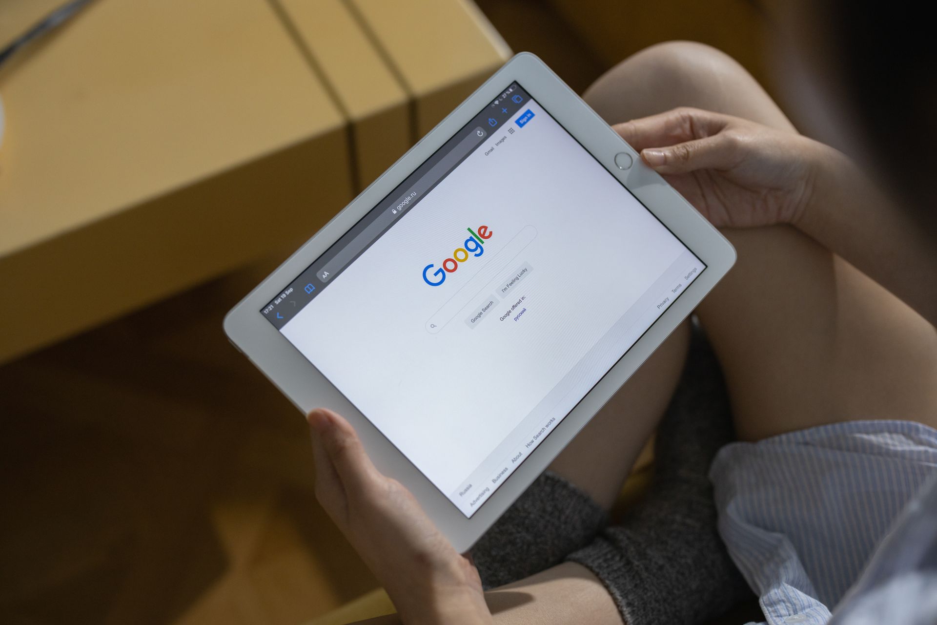 Hands holding a tablet showing a Google search page